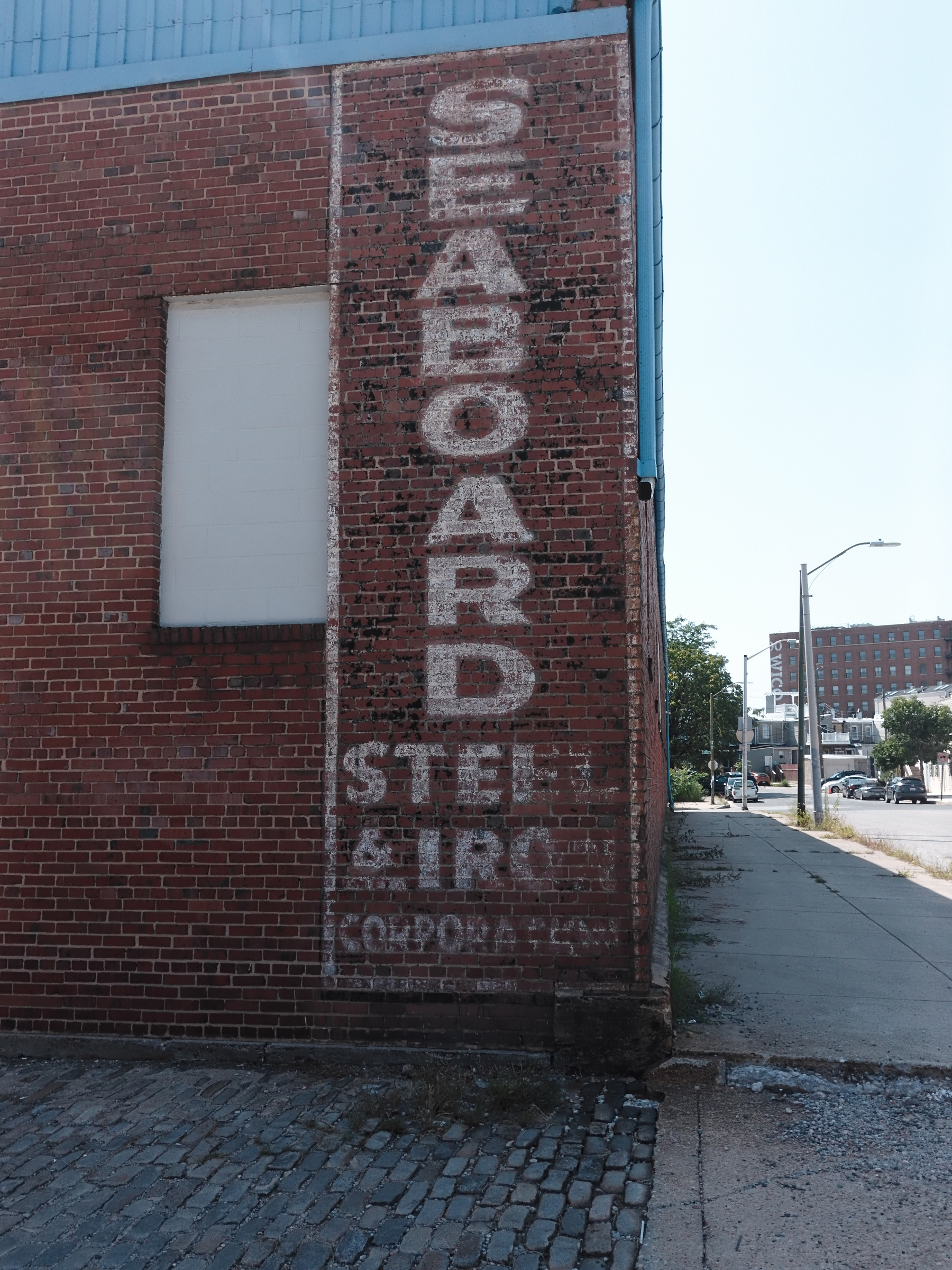 A faded vertical sign painted on a red brick wall reads SEABOARD STEEL & IRON CORPORATION.